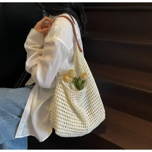 Detail of white crochet knit tote bag with hollow out design and brown leather strap