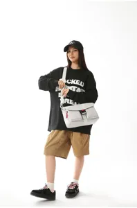 Elegante bolso bandolera funcional gris claro usado por una modelo en un estudio profesional