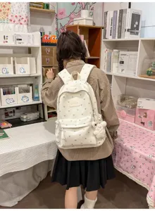 Detailed back view of a white heart pattern student backpack featuring a cute plush toy