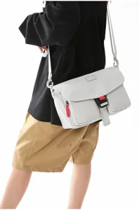 Vista lateral detallada de una bolsa de mensajero techwear funcional gris claro en el modelo