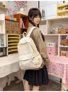 Detail view of a white heart-patterned backpack worn by a student in a cozy room setting