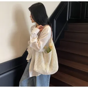 Close-up of a white hollow knit mesh shoulder bag with floral props on model's shoulder