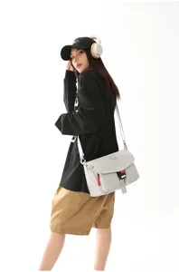 Vista completa de un modelo con un bolso bandolera funcional gris claro en un estudio