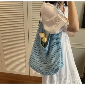 Close-up of a blue hollow-out crochet shoulder bag worn with a summer white dress