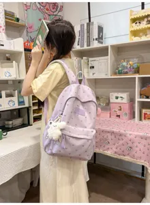 Lifestyle shot of a purple casual student backpack with heart patterns and plush charm