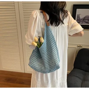 Detail view of a blue hollow knit tote bag with leather strap in a lifestyle setting