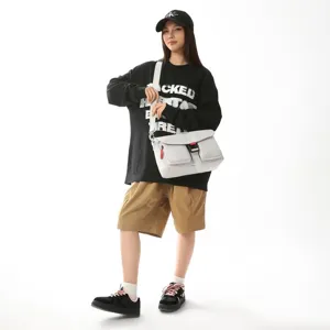 Modelo con un bolso mensajero funcional gris con bolsillos y correa ancha ajustable para el hombro