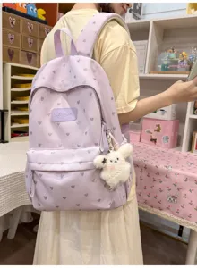 Student wearing a purple casual backpack with heart prints and a cute plush charm