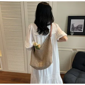 Back view of a woman carrying a beige knitted mesh shoulder bag with flowers inside