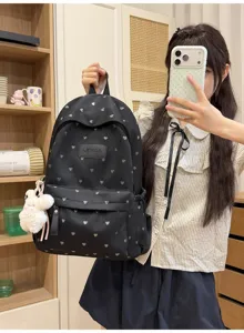 Detailed view of black backpack featuring silver heart pattern and plush bunny charm