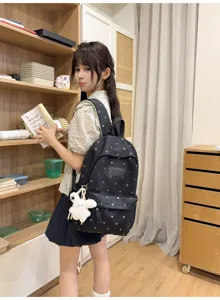 Detailed view of black commuter student backpack featuring heart patterns and white bunny pendant