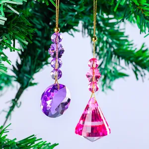 Twee kleurrijke facetgeslepen kristallen kerstversieringen aan een groene dennentak.