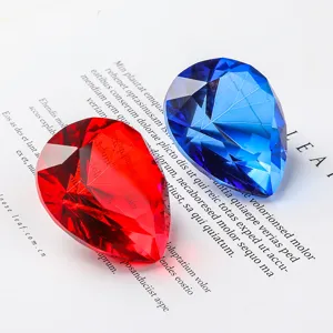 Close-up of red and blue pear-shaped faceted crystal stones on magazine background