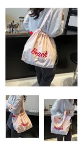 Detalle del bolso hobo rosa con bordado Beach rojo llevado por una modelo asiática