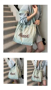 Vista detallada de un bolso tote grande de lona verde salvia con el estampado 'Beach' en modelo