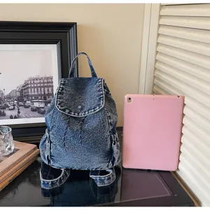 Vintage denim backpack with drawstring closure shown next to a tablet for scale
