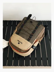 Vista detallada de una mochila de senderismo marrón con paneles de malla en mesa negra.