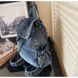 Macro view of a vintage washed denim backpack with drawstring and elastic side pockets.