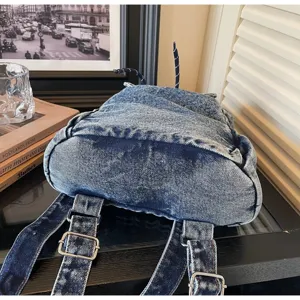 Close-up detail of retro denim backpack showing sturdy bottom and adjustable straps
