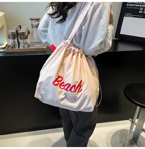 Bolso tote rosa informal de gran capacidad con bordado Beach rojo usado por modelo