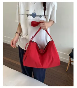 Große rote wasserdichte Nylon-Schultertasche, lässig getragen von einem Modell im Detail