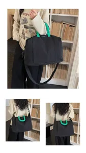 Close-up detail of a large black travel bag featuring green handles and adjustable strap