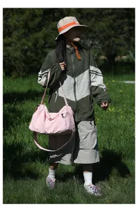 Modèle portant un grand sac à bandoulière rose en tissu Oxford pour voyage en plein air