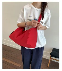Modell trägt eine rote wasserdichte Nylon-Umhängetasche in einer Lifestyle-Umgebung