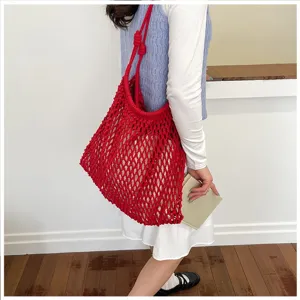 Détail d'un sac cabas en macramé rouge montrant la texture ajourée et la couleur vive.