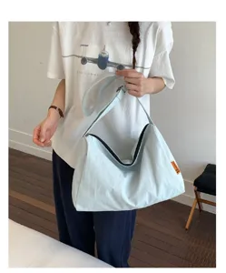 Modell trägt eine minimalistische hellblaue Nylon-Tragetasche mit großer Kapazität.