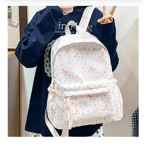 Vista detallada de una linda mochila escolar blanca con patrones de lazos y flores rosas