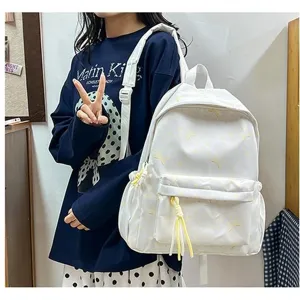 Vista lateral de la mochila blanca de estilo coreano con patrones amarillos y borlas