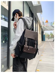 Vista lateral de un modelo con una mochila vintage de lona negra y detalles de cuero