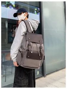 Mochila de lona vintage llevada por una persona, muestra gran capacidad y diseño gris retro.