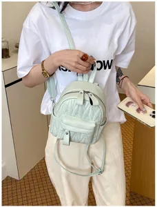 Detailweergave van een mintgroene gewatteerde minirugzak gedragen door een model in een casual look.