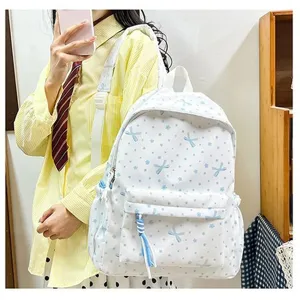 Detalle de una elegante mochila blanca para estudiantes con un lindo diseño de lazo azul.