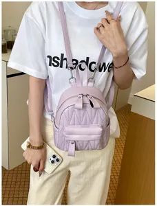 Detailweergave van een paarse mini gewatteerde rugzak gedragen door een model in casual outfit