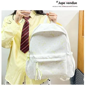 Vista detallada de la mochila blanca con bonitos bordados de lazos amarillos.