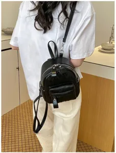 Stijlvolle zwarte gewatteerde mini rugzak gedragen bij een witte casual outfit.