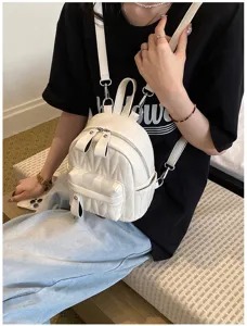 Detail van een witte gewatteerde mini rugzak gedragen als modeaccessoire