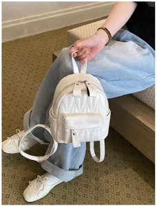Gedetailleerd overzicht van een stijlvolle witte gewatteerde mini rugzak in een casual setting