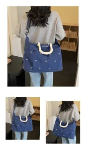 Close-up detail of a large capacity navy blue travel bag with white bow patterns on model
