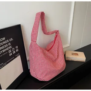 Macro view of a red and white checkered canvas tote bag in a minimalist lifestyle setting.