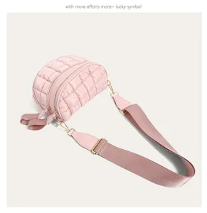 Side angled view of a pink quilted puffy shoulder bag with wide adjustable strap