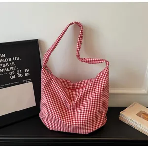 Red and white checkered nylon tote bag with zipper closure on a black table background