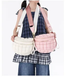 Detailed view showing the quilted texture of cream and pink puffer crossbody bags on a model.