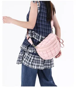 Stylish pink quilted crossbody chest bag worn by a female model over a plaid dress