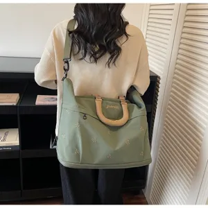 Back view of a large green travel bag with bow embroidery and beige handles
