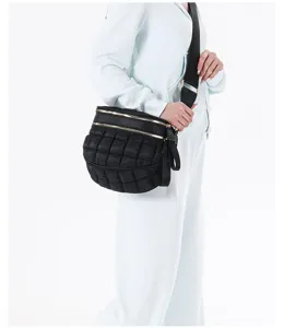 Side view of a black quilted puffy chest bag worn by a model in a light tracksuit.