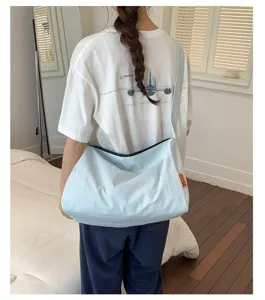 Rückansicht eines Modells, das die Passform der hellblauen Nylon-Schultertasche demonstriert